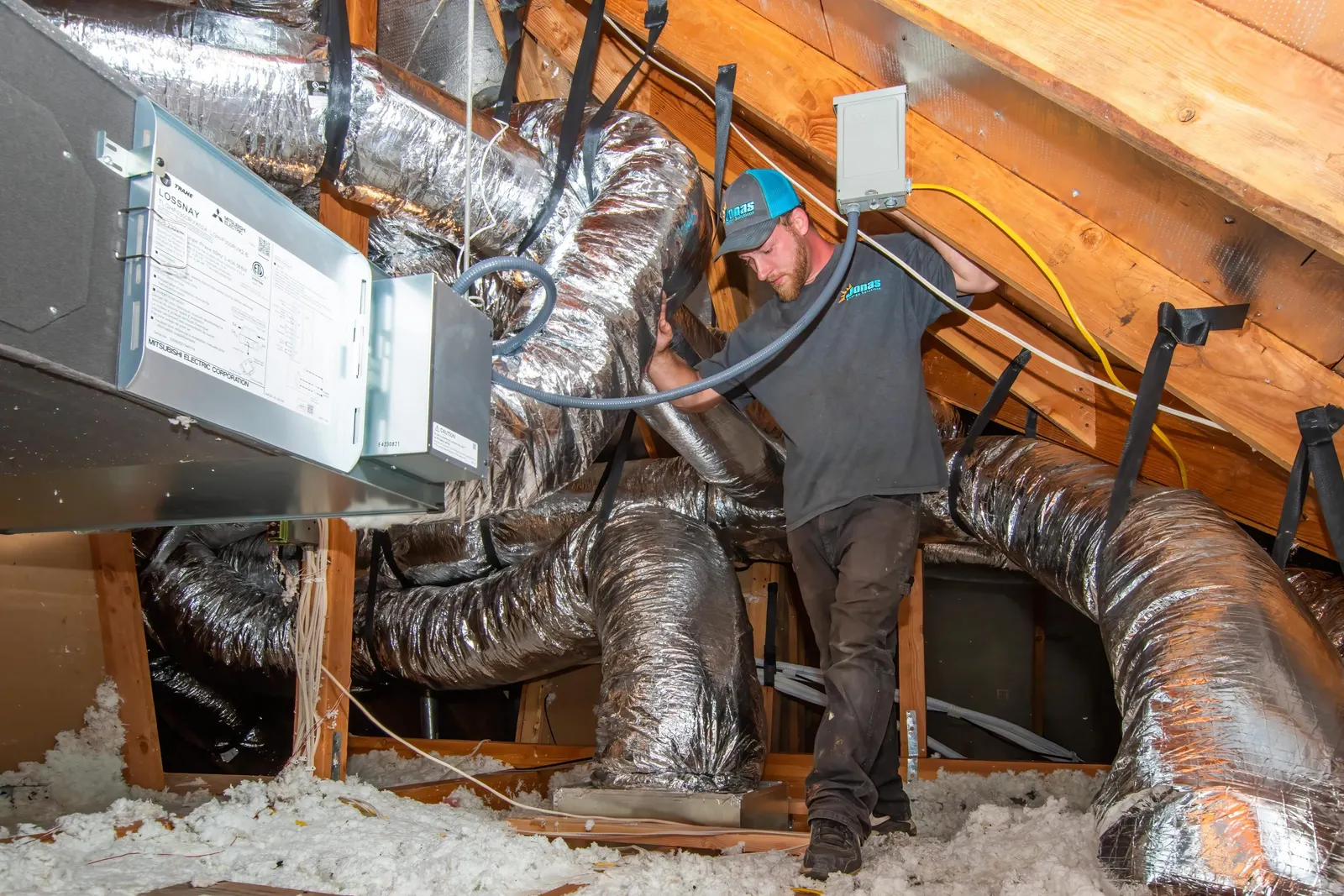 Jonas Energy technician inside an attic during HVAC installation.